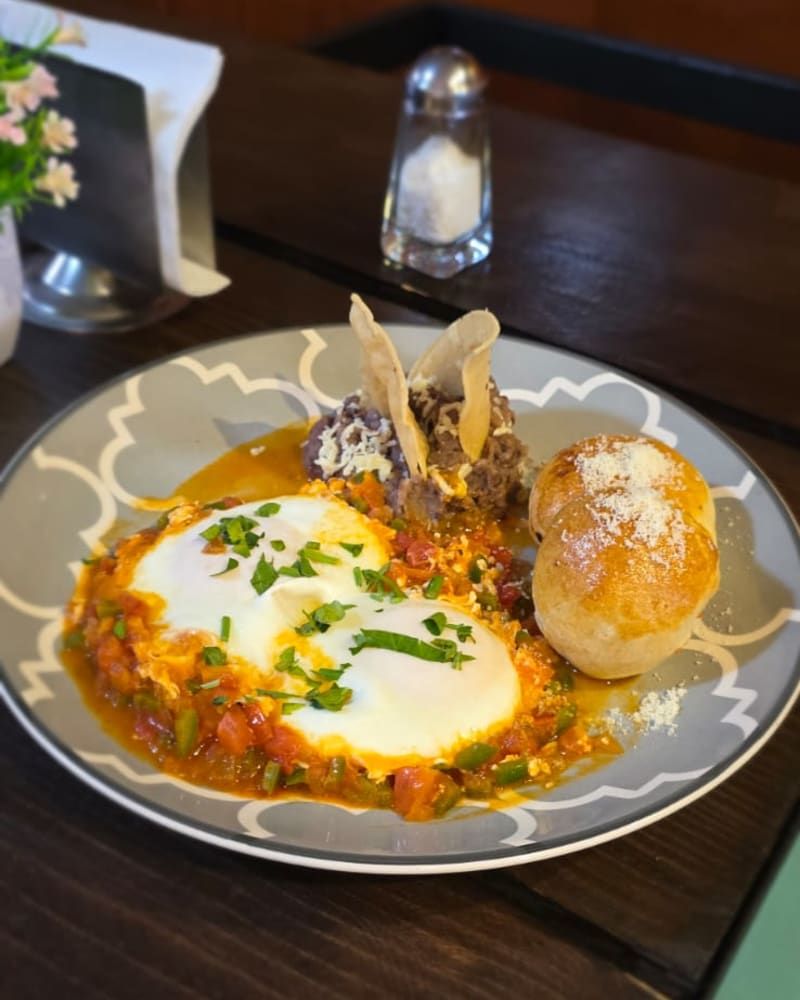 Huevos en salsa con pan, servidos en plato de cerámica